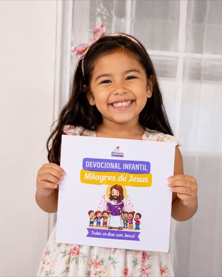 Menina sorrindo segurando o material da BíbliaMania